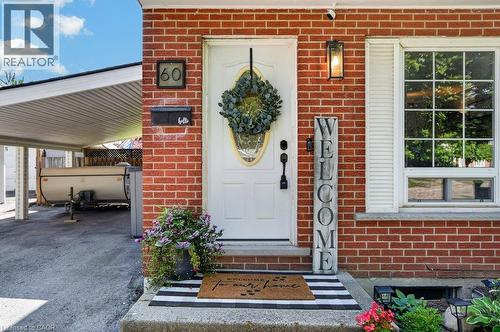 Brick exterior with white front door, transom window, and a carport - 60 Elford Crescent, Hamilton, ON - Outdoor With Exterior