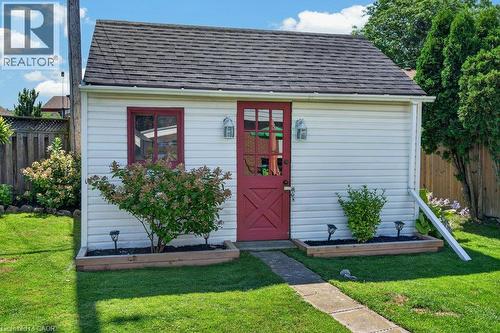 Charming cottage-style home featuring a distinctive red Dutch door entry, white horizontal siding, and a pitched roof with dark shingles - 60 Elford Crescent, Hamilton, ON - Outdoor