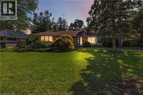 Single-story residence featuring a classic facade, a prominent front lawn, mature trees, and established foundational plantings - 974 Unsworth Avenue, Burlington, ON 