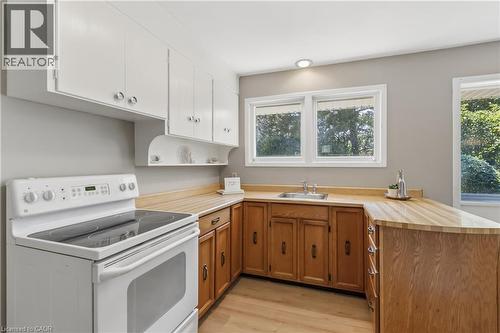 Kitchen featuring white upper cabinetry, natural wood-finish lower cabinetry, wood-finish countertops, stainless steel sink, and wood-finish flooring - 974 Unsworth Avenue, Burlington, ON 