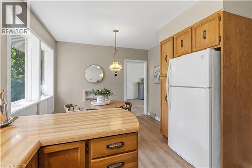 Bright and spacious kitchen featuring natural wood cabinetry with ample storage, a wood-finish island with drawers, stainless steel appliances including a refrigerator, and pendant lighting - 974 Unsworth Avenue, Burlington, ON 