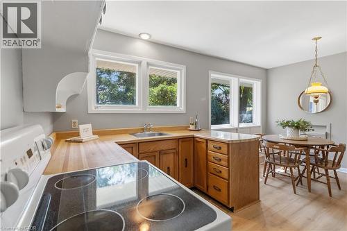 Bright, open kitchen featuring wood-finish cabinetry, wood countertops, and stainless steel appliances including a cooktop with dual burners - 974 Unsworth Avenue, Burlington, ON 