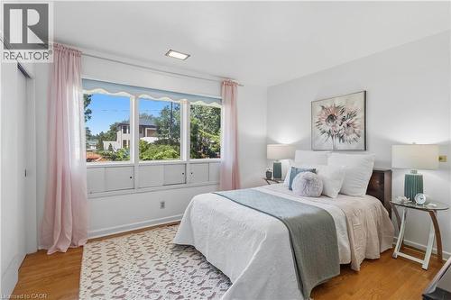 Bright bedroom featuring hardwood flooring, large multi-pane windows with natural light, and pink curtain panels - 974 Unsworth Avenue, Burlington, ON 