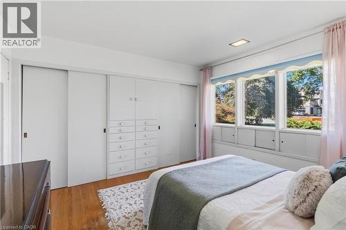 Bright bedroom featuring hardwood flooring, ample natural light from multi-pane windows, and extensive built-in cabinetry with drawers and shelving - 974 Unsworth Avenue, Burlington, ON 