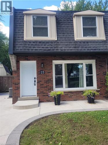 Charming brick home featuring a welcoming front facade with dual dormer windows, dark architectural shingle roofing, and white trim accents - 23 Bentley Place, Hamilton, ON - Outdoor With Exterior