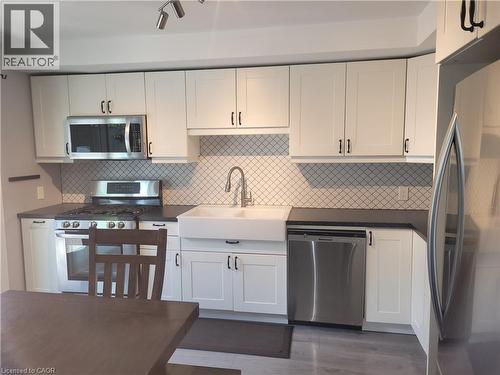 Modern kitchen featuring white shaker-style cabinetry with brushed nickel hardware, a geometric tile backsplash, and stainless steel appliances including a gas range, built-in microwave, and dishwashe - 23 Bentley Place, Hamilton, ON - Indoor Photo Showing Kitchen With Stainless Steel Kitchen With Upgraded Kitchen