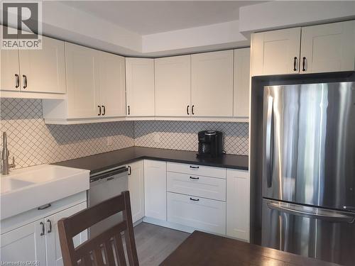 Modern kitchen featuring crisp white cabinetry with brushed nickel hardware, a geometric tile backsplash, and stainless steel appliances including a refrigerator with French doors - 23 Bentley Place, Hamilton, ON - Indoor Photo Showing Kitchen