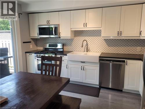 Updated Kitchen with Shaker-Style Cabinetry, Stainless Steel Appliances, and Quartz Countertops This bright kitchen features crisp white cabinetry with brushed nickel hardware, a geometric tile backs - 23 Bentley Place, Hamilton, ON - Indoor Photo Showing Kitchen With Stainless Steel Kitchen
