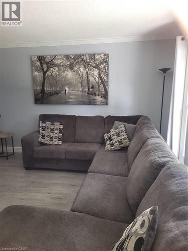 Comfortable living room featuring a sectional sofa arrangement with neutral upholstery, decorative throw pillows, and wood-finish flooring - 23 Bentley Place, Hamilton, ON - Indoor Photo Showing Living Room