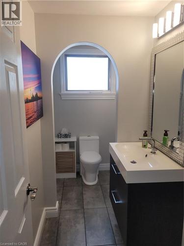 Modern bathroom featuring a sleek white rectangular vessel sink with matte black wall-mounted faucet, floating vanity with integrated storage, and contemporary toilet - 23 Bentley Place, Hamilton, ON - Indoor Photo Showing Bathroom