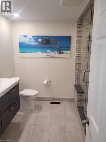 Modern bathroom featuring a sleek dark vanity with integrated sink, white ceramic toilet, and tile flooring in neutral tones - 23 Bentley Place, Hamilton, ON - Indoor Photo Showing Bathroom