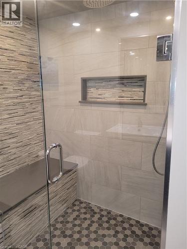 Spa-inspired master bath featuring a frameless glass walk-in shower enclosure with dual showerheads, linear mosaic accent wall, and a recessed niche - 23 Bentley Place, Hamilton, ON - Indoor Photo Showing Bathroom