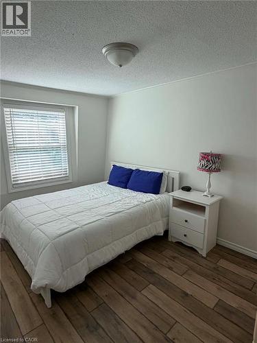 Bedroom featuring wood-finish flooring, a window with horizontal blinds, and a flush-mount ceiling light fixture - 23 Bentley Place, Hamilton, ON - Indoor Photo Showing Bedroom
