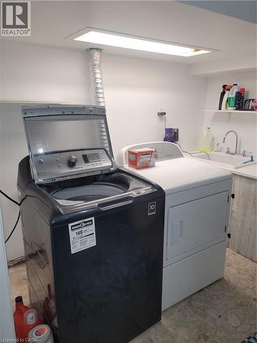 Dedicated laundry room featuring a full-size top-load washer and electric dryer with stacked configuration, recessed ceiling lighting, laminate countertops, and utility sink with chrome faucet - 23 Bentley Place, Hamilton, ON - Indoor Photo Showing Laundry Room