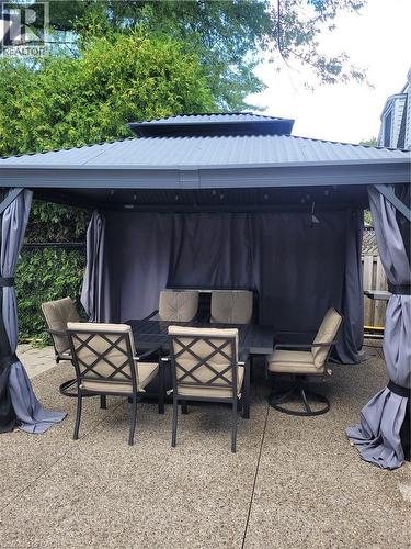 Outdoor gazebo featuring a corrugated metal roof, privacy curtains, and string lighting - 23 Bentley Place, Hamilton, ON - Outdoor With Deck Patio Veranda