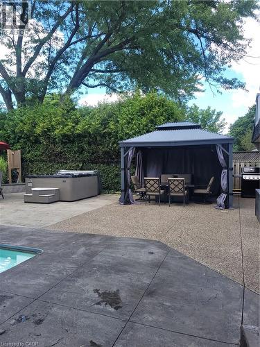 Expansive backyard oasis featuring mature shade trees, stamped concrete patio, resort-style gazebo with integrated seating area, built-in fire pit with stone surround, and manicured landscaping with p - 23 Bentley Place, Hamilton, ON - Outdoor With In Ground Pool With Deck Patio Veranda