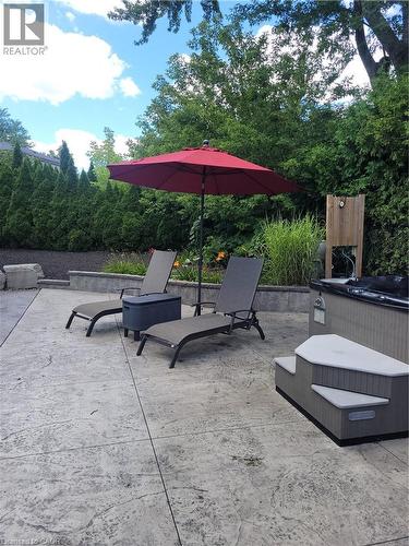 Stamped concrete patio featuring privacy landscaping and a hot tub with coordinating steps - 23 Bentley Place, Hamilton, ON - Outdoor With Backyard