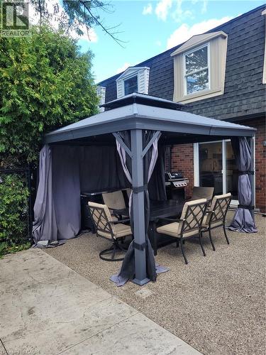 Expansive outdoor patio area featuring a large, freestanding gazebo with privacy curtains and a durable, textured concrete surface - 23 Bentley Place, Hamilton, ON - Outdoor With Deck Patio Veranda