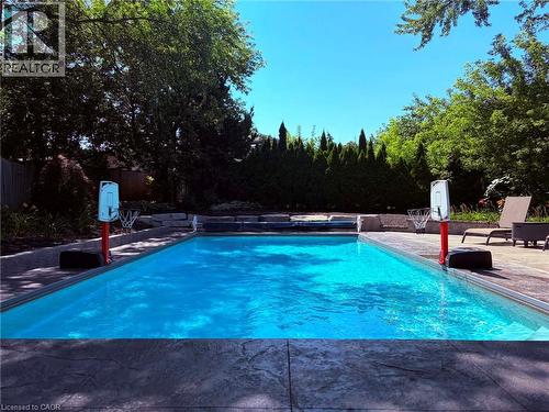 In-ground swimming pool with stamped concrete decking, surrounded by mature trees and privacy landscaping - 23 Bentley Place, Hamilton, ON - Outdoor With In Ground Pool With Backyard