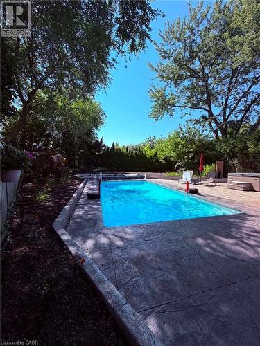 In-ground swimming pool featuring a patterned concrete surround and an adjacent hot tub - 23 Bentley Place, Hamilton, ON - Outdoor With In Ground Pool With Backyard