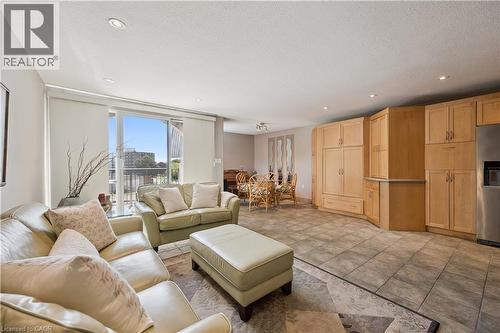 Open-concept living space featuring a sliding glass door to a balcony, recessed lighting, expansive wood-finish cabinetry, and stainless steel appliances - 36 Hayhurst Road Unit# 329, Brantford, ON - Indoor Photo Showing Living Room