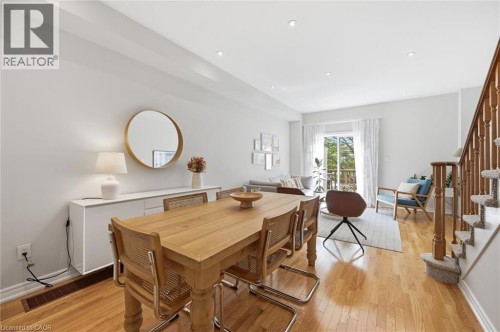 Open-concept living area featuring wood-finish flooring, recessed lighting, white wall paint, a sliding glass door leading to an outdoor space, and a wooden staircase with carpeted treads - 678 Rowley Common, Burlington, ON - Indoor Photo Showing Dining Room