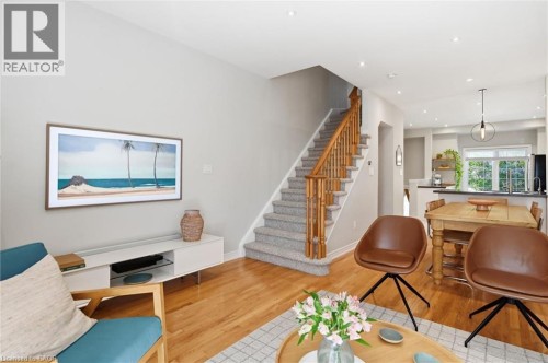 Light-filled interior featuring wood-finish flooring and a carpeted staircase with wood banisters - 678 Rowley Common, Burlington, ON - Indoor