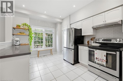 Bright and updated kitchen featuring white cabinetry, stainless steel appliances including a double wall oven, tile flooring, and abundant natural light from multiple windows - 678 Rowley Common, Burlington, ON - Indoor Photo Showing Kitchen With Stainless Steel Kitchen