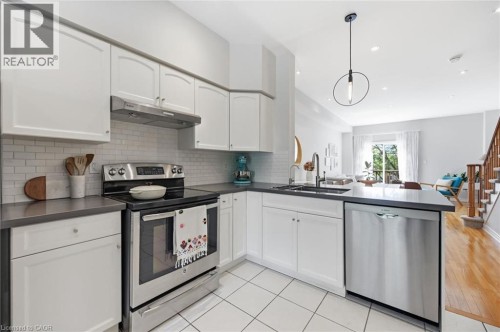 Modern kitchen featuring white cabinetry, subway tile backsplash, stainless steel appliances, and dark countertops - 678 Rowley Common, Burlington, ON - Indoor Photo Showing Kitchen With Stainless Steel Kitchen With Upgraded Kitchen