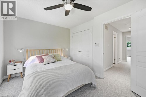 Bedroom featuring light grey walls, textured carpeting, a ceiling fan with integrated lighting, and white bi-fold closet doors - 678 Rowley Common, Burlington, ON - Indoor Photo Showing Bedroom