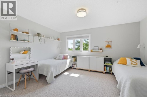 Neutral-toned bedroom featuring a large window, carpeted flooring, a flush-mount ceiling light fixture, and built-in shelving and cabinetry - 678 Rowley Common, Burlington, ON - Indoor Photo Showing Bedroom