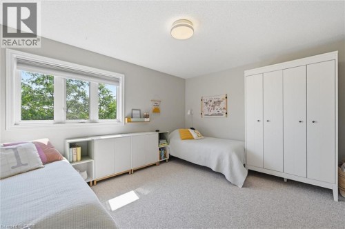 Room featuring light gray walls, textured light-colored carpeting, and a white ceiling with a flush-mount light fixture - 678 Rowley Common, Burlington, ON - Indoor Photo Showing Bedroom