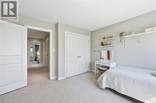 Light-colored wall-to-wall carpeting throughout, featuring a double-door closet with white panel doors and brushed nickel hardware - 678 Rowley Common, Burlington, ON - Indoor Photo Showing Bedroom