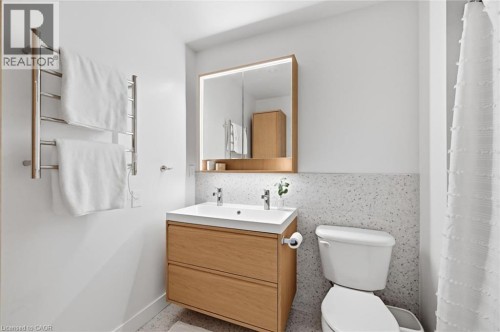 Modern bathroom featuring a floating wood-finish vanity with an integrated sink, illuminated medicine cabinet, and a towel warming rack - 678 Rowley Common, Burlington, ON - Indoor Photo Showing Bathroom