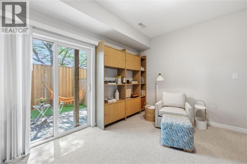 Bright, light-filled room featuring glass sliding doors opening to private outdoor space, neutral carpeting, and substantial wood-finish cabinetry with open shelving - 678 Rowley Common, Burlington, ON - Indoor
