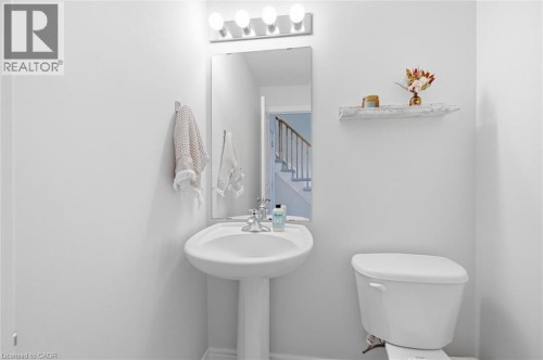 Pedestal sink with chrome fixtures, a rectangular mirror, and a four-bulb vanity light - 678 Rowley Common, Burlington, ON - Indoor Photo Showing Bathroom
