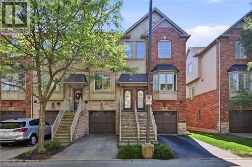 Brick and stone facade townhome featuring a private entrance, covered porch, and integrated garage - 678 Rowley Common, Burlington, ON - Outdoor With Facade