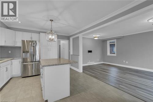 Open-concept kitchen and living area featuring white cabinetry, stainless steel refrigerator, a center island with a granite-style countertop, and recessed lighting - 197 Troy Street, Mississauga, ON - Indoor Photo Showing Kitchen