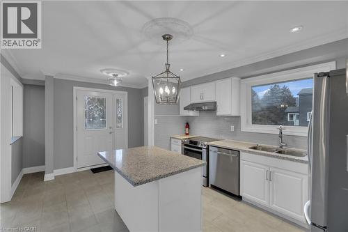 Contemporary kitchen featuring white cabinetry, stainless steel appliances, a light-toned stone countertop island, and a subway tile backsplash - 197 Troy Street, Mississauga, ON - Indoor Photo Showing Kitchen With Double Sink With Upgraded Kitchen