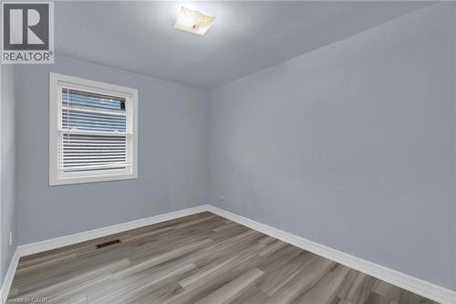 Room featuring light gray walls, wood-finish flooring, white baseboards, and a white-framed window with horizontal blinds - 197 Troy Street, Mississauga, ON - Indoor Photo Showing Other Room