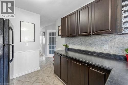 Kitchen featuring dark wood-finish cabinetry, a textured backsplash, and contrasting countertops - 33 Remple Court, Cambridge, ON - Indoor Photo Showing Kitchen