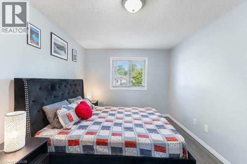 Light gray painted walls define this room featuring wood-finish flooring and a single window with white blinds - 33 Remple Court, Cambridge, ON - Indoor Photo Showing Bedroom