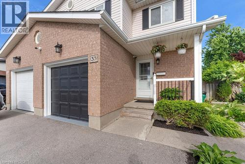 Brick and siding exterior featuring two garage doors, a covered entry, and established landscaping - 33 Remple Court, Cambridge, ON - Outdoor With Exterior