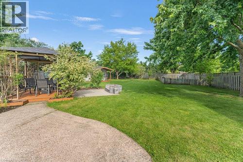 Expansive backyard featuring a lush lawn, concrete patio, and a built-in stone fire pit - 33 Remple Court, Cambridge, ON - Outdoor