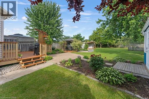 Expansive backyard featuring a wood deck with steps, a concrete pathway, a gravel patio, mature greenery, and a shed - 33 Remple Court, Cambridge, ON - Outdoor With Deck Patio Veranda With Backyard