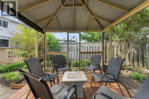 Spacious screened gazebo featuring a wood-finish floor, exposed beam ceiling, stone-look fire pit base, and surrounding mature landscaping - 33 Remple Court, Cambridge, ON - Outdoor With Deck Patio Veranda With Exterior