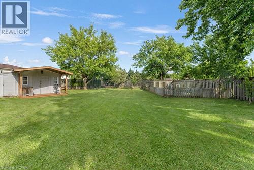 Expansive backyard featuring a large shed with an attached covered wood deck, manicured lawn, mature trees, and perimeter fencing - 33 Remple Court, Cambridge, ON - Outdoor