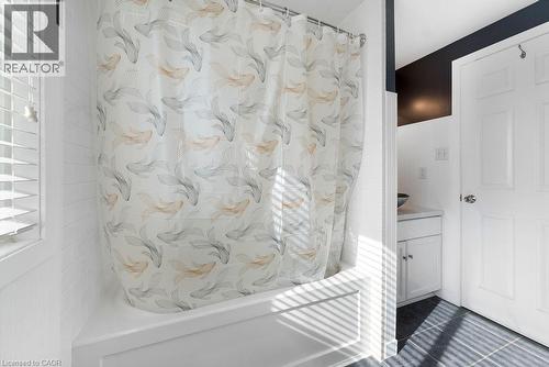 Bathroom featuring a white bathtub with subway tile surround, white paneled walls, and a window with horizontal blinds - 33 Remple Court, Cambridge, ON - Indoor Photo Showing Bathroom