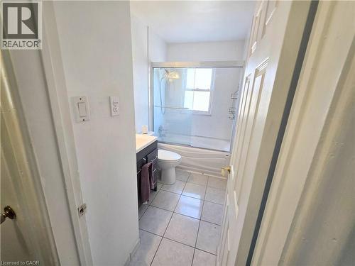 White tile flooring, dark wood-finish vanity with countertop, built-in toilet, and shower with glass enclosure - 353 East 21St Street, Hamilton, ON - Indoor Photo Showing Bathroom