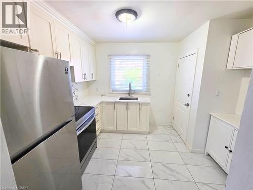 Kitchen featuring white cabinetry, white countertops, tile flooring, stainless steel appliances, and a window with blinds - 353 East 21St Street, Hamilton, ON - Indoor Photo Showing Kitchen